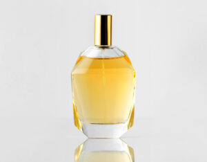 front view yellow fragrance bottle with golden cap white wall