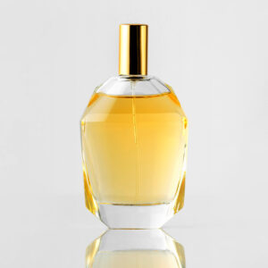 front view yellow fragrance bottle with golden cap white wall